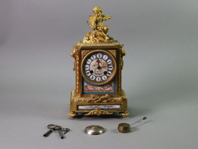 a gold clock with a statue on top of it next to a bunch of keys