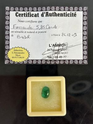 a green jade stone in a yellow box with a certificate