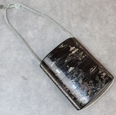 un sac à main noir avec une poignée argentée sur un fond gris