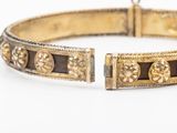 a close up of a gold bracelet on a white surface