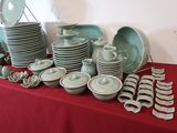 many plates and bowls on a table with a red table cloth
