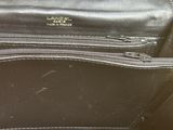the inside of a black purse with a gold chain hanging from it