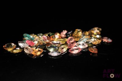 a close up of a pile of multi colored gems on a black surface