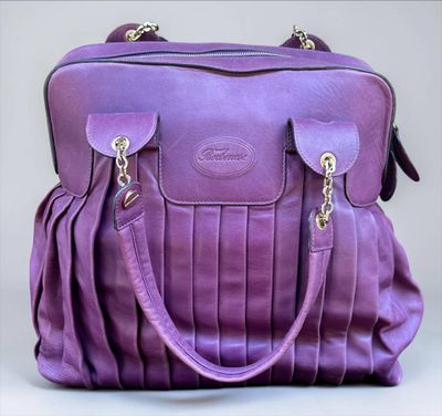 the purple purse is sitting on a white surface with a gray background