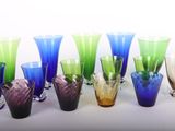 plusieurs vases en verre de différentes couleurs sont alignés sur une surface blanche