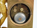 a gold clock with a statue of a man standing next to it