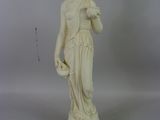 une statue blanche représentant une femme tenant une fleur