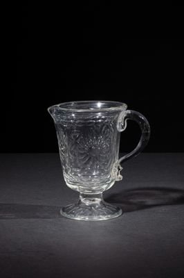a glass cup sitting on a table with a black background