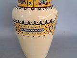 a white vase with a yellow and blue design on it