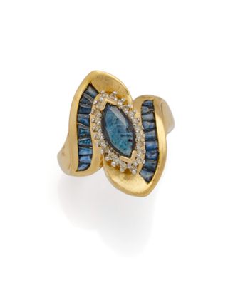 gros plan d'une bague en or avec des pierres bleues et blanches