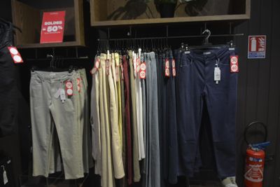 many different colored pants hanging on a rack in a store