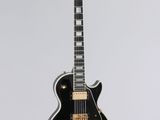 une guitare électrique noire accrochée à un mur blanc