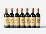 six bottles of wine are lined up in a row on a white surface
