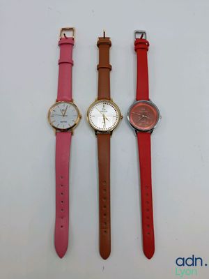 trois montres de couleurs différentes placées l'une à côté de l'autre sur une surface blanche