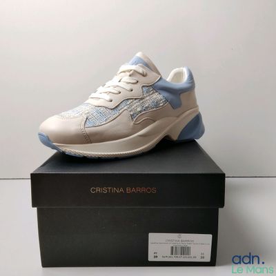 Les baskets blanches et bleues sont posées sur une boîte noire
