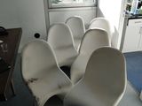 quatre chaises blanches dans une pièce avec une fenêtre en arrière-plan