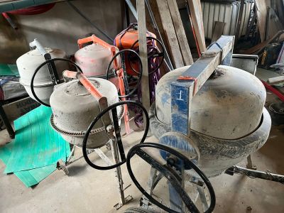 a cement mixer sitting in a garage with other tools