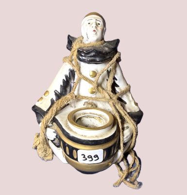une figurine représentant un homme assis sur un pot