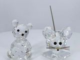 pair of clear crystal mouse figurines sitting on a white surface