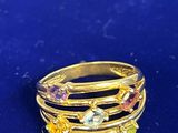 une image représentant une bague en or sertie de pierres multicolores sur un fond bleu