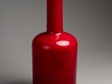 un vase rouge avec un couvercle blanc posé sur une surface grise