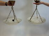 two people holding a pair of glass bowls with chains