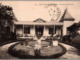 une vieille photo d'une maison avec une fontaine devant