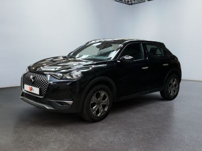 Un SUV noir est garé dans une grande pièce équipée d'un ventilateur de plafond.