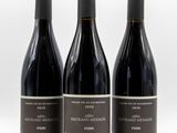 trois bouteilles de vin sont alignées sur une surface blanche