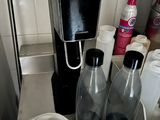 a coffee maker sitting on a counter next to two empty bottles
