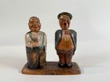 pair of wooden figurines of two men standing on a wooden base