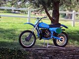 a blue dirt bike parked in front of a white fence