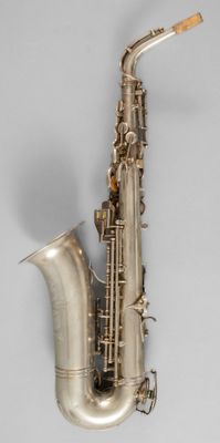 an old silver saxophone with a wooden handle on a gray background