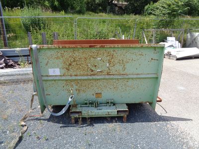 a green dumpster sitting in the middle of a parking lot