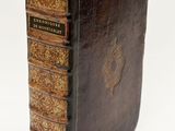 an old book with a brown cover sitting on top of a white surface