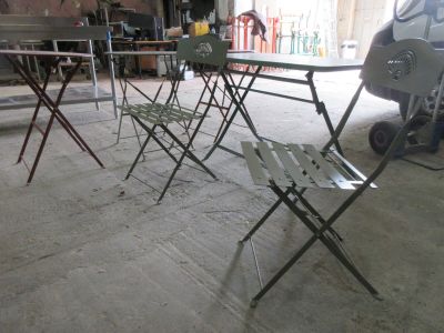 plusieurs chaises pliantes et une table dans un garage, avec un camion en arrière-plan