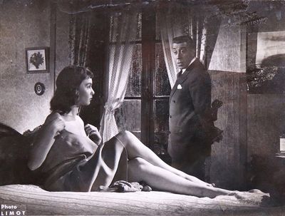 a black and white photo of a woman sitting on a bed next to a man