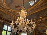un lustre au milieu d'une pièce dont le plafond est orné d'une peinture