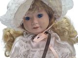 a doll with blonde hair wearing a white dress and a hat