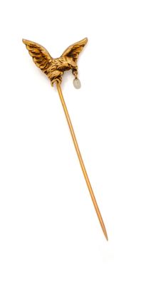 une image représentant une broche en forme d'oiseau doré ornée de perles, sur fond blanc