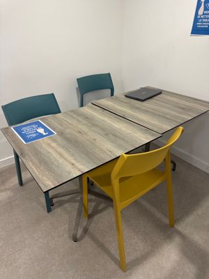 une table et deux chaises dans une pièce où est accrochée une pancarte au mur