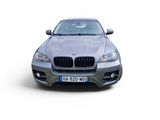 the front of a silver bmw suv parked on a white surface