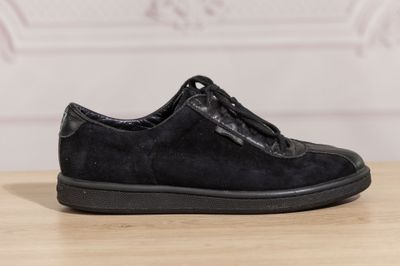 the black shoe is on a wooden table with a white wall in the background