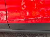 a red car with a reflection of a man on the side of it