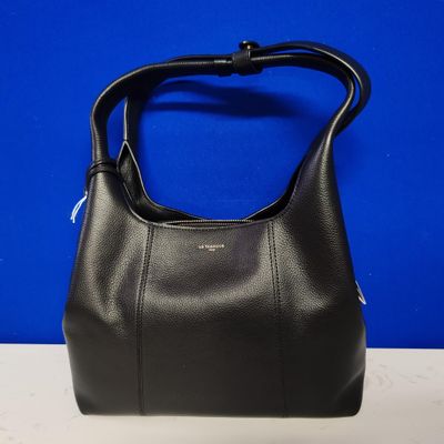 a black leather handbag on a table against a blue background