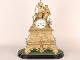 une horloge dorée posée sur un socle vert