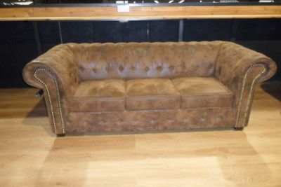 brown leather couch sitting in front of a bar in a room