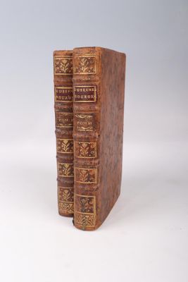 two old books sitting on top of each other on a white surface