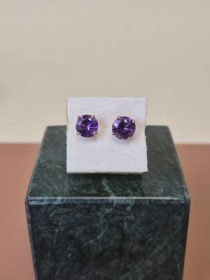 une paire de boucles d'oreilles en amethorate posées sur un bloc de marbre