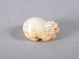 an ivory figurine of a sheep with a white body on a gray surface